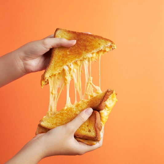 A person holding a slice of cheese and a piece of bread, ready to prepare a snack or meal.